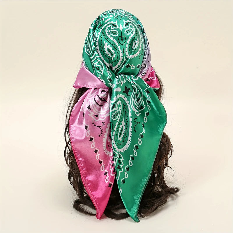 A vibrant green satin silk scarf tied in a bow with pink accents, displayed on dark hair.