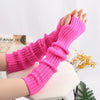 A close-up of bright pink knitted fingerless gloves being worn on a hand against a white background.