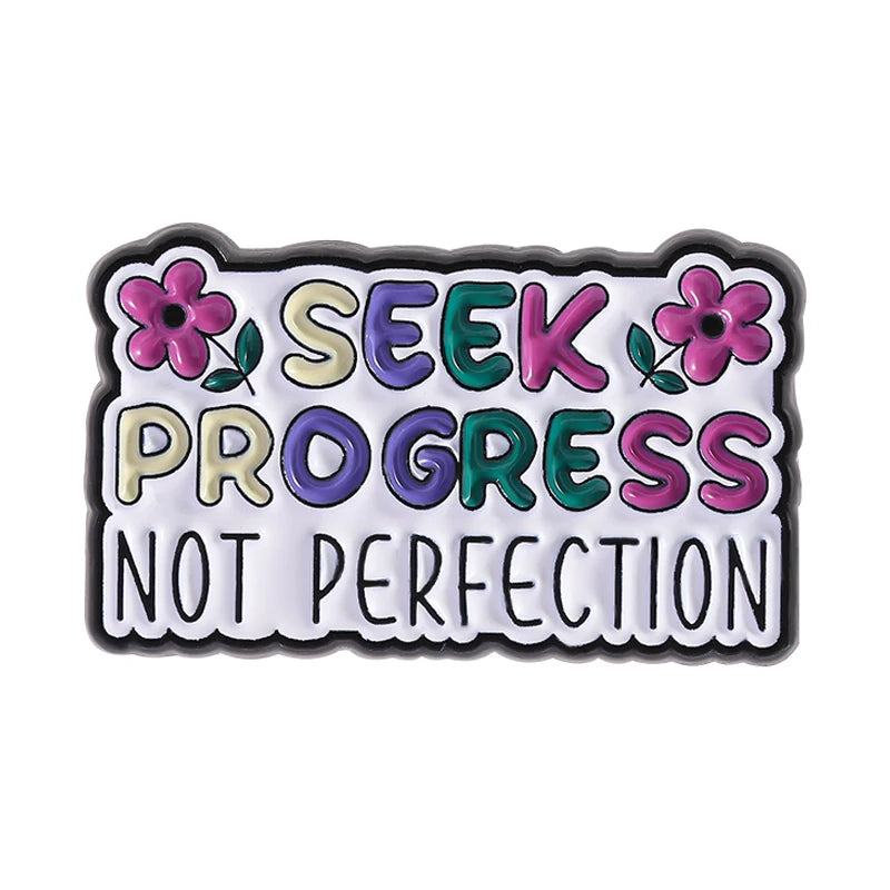 Enamel pin featuring the quote Seek Progress Not Perfection in colorful lettering and flowers