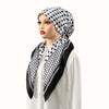 A woman wearing a black and white patterned satin silk hijab headband cap with a white top.