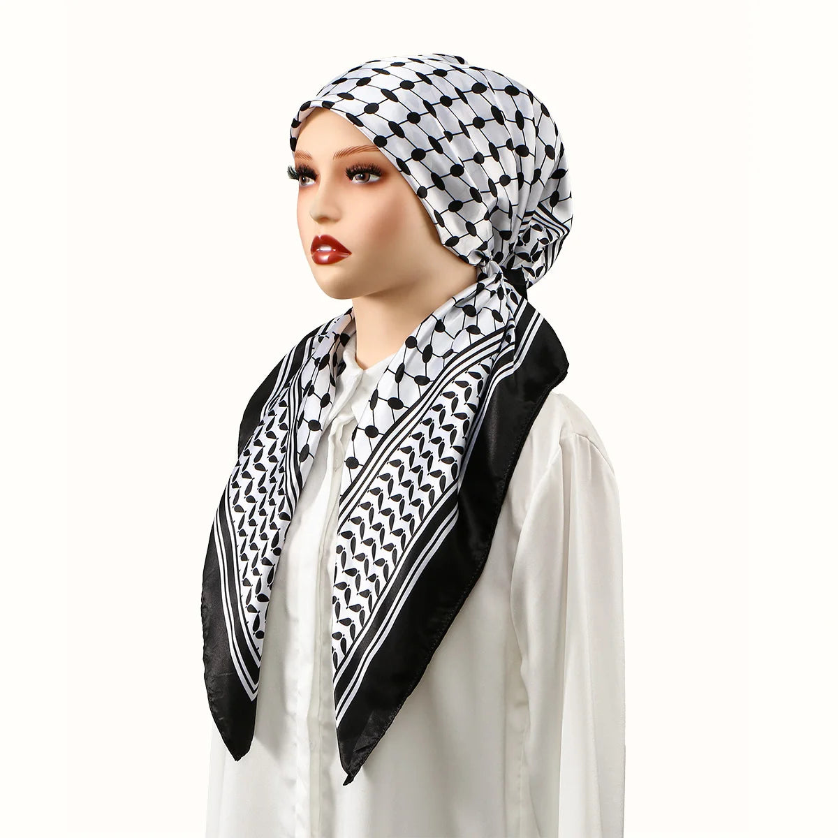 A woman wearing a black and white patterned satin silk hijab headband cap with a white top.