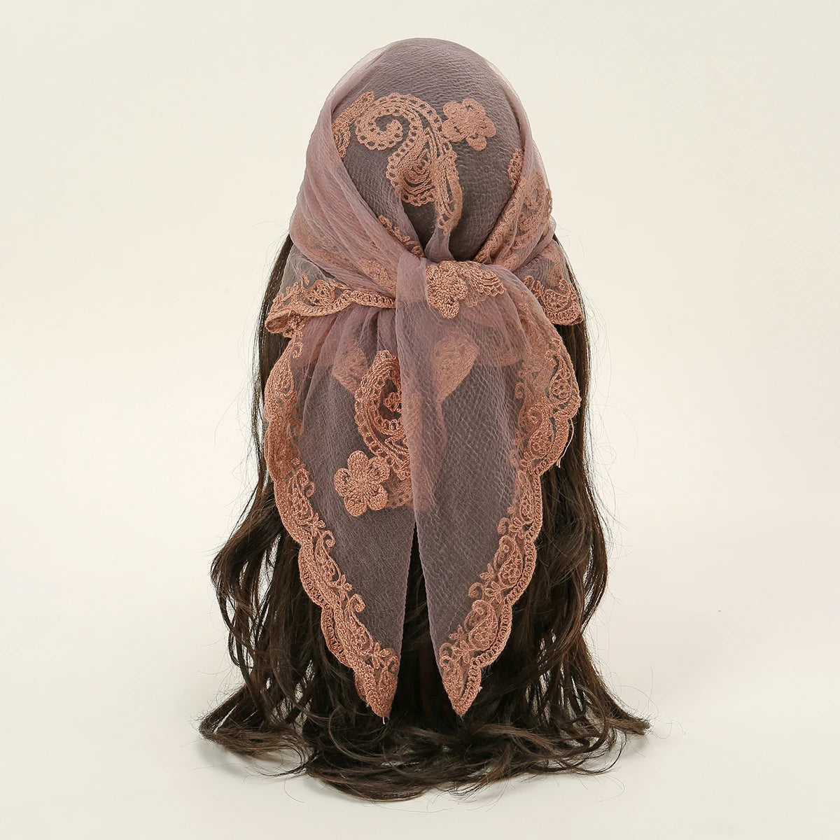 A sheer, dusty rose floral embroidered lace bandana headscarf tied around dark hair.