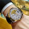 A gold-toned luxury automatic mechanical wristwatch worn on a wrist, featuring a white dial and silver casing.