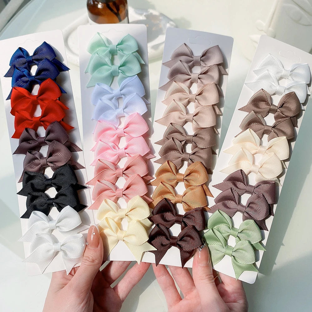 Colección de clips para el pelo con lazos de color sólido para niños, mostrados en una tarjeta blanca contra un fondo claro.