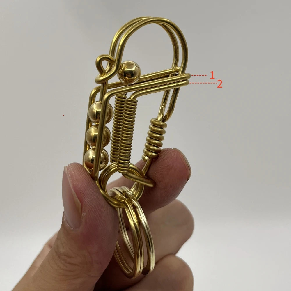 Gros plan d'un porte-clés mécanique en acier inoxydable de couleur or avec mécanisme à ressort tenu par une main.
