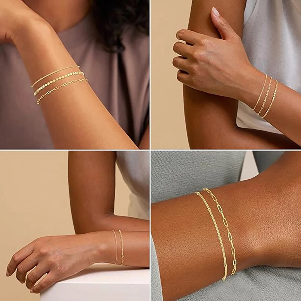 A set of dainty gold plated stackable bracelets worn on a wrist and hand.