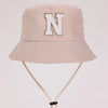 A light beige sun hat with a large white letter N embroidered on the front.
