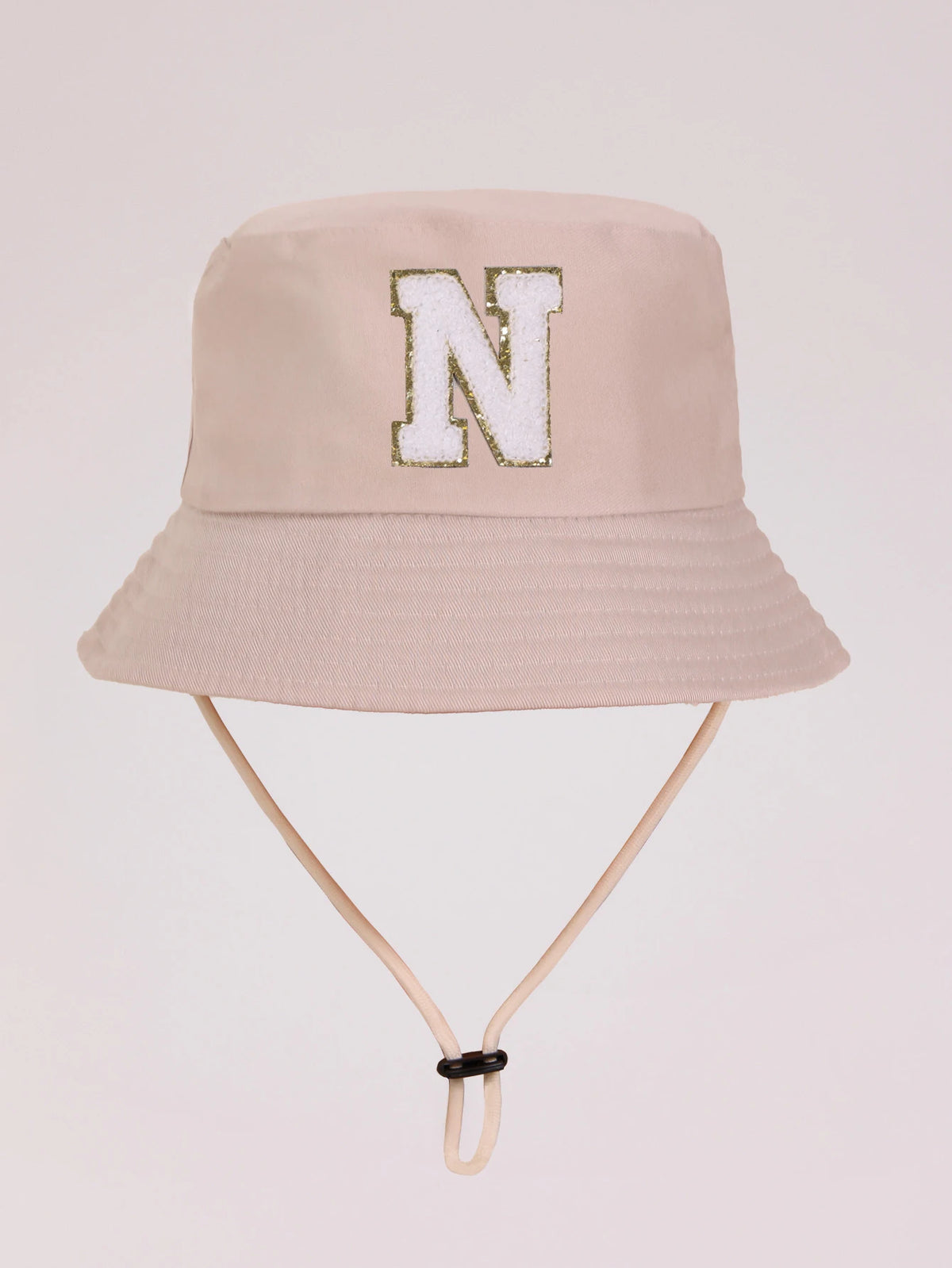 A light beige sun hat with a large white letter N embroidered on the front.