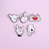 A collection of white enamel pins depicting various cartoon finger gestures, including a pointing finger and a heart hand.