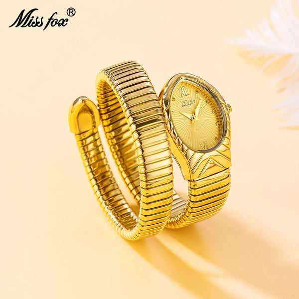 A close-up shot of a gold-toned ladies watch with a snake design on the strap, resting on a light background.