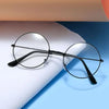 Un par de gafas redondas de metal negro sobre una superficie blanca texturizada contra un fondo azul.