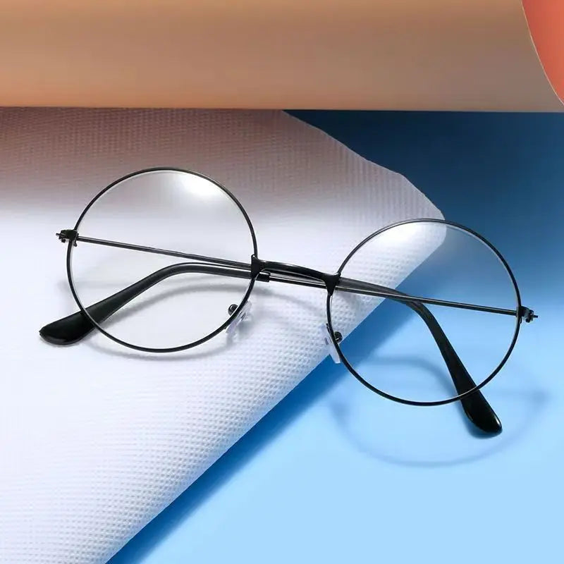Un par de gafas redondas de metal negro sobre una superficie blanca texturizada contra un fondo azul.
