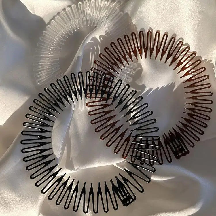 Gros plan d'un paquet de deux pinces à cheveux en diamant stretch en plastique noir et marron sur un tissu satiné blanc.