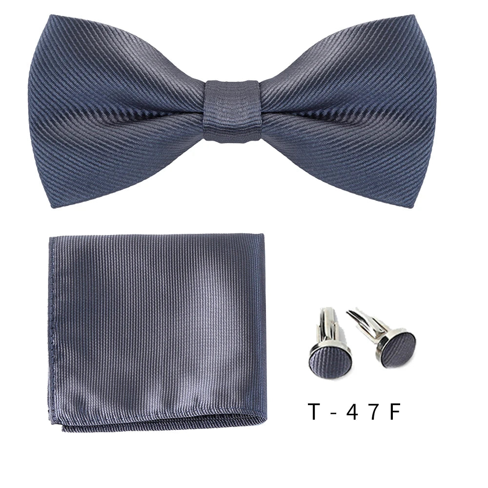 A dark gray bow tie and cufflinks set displayed on a white background.