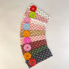 A display of vintage polka dot button headbands in various shades of pink, green, and brown arranged in a fan shape.