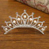 A sparkling crystal princess tiara hair comb adorned with pearls resting on a wooden surface.