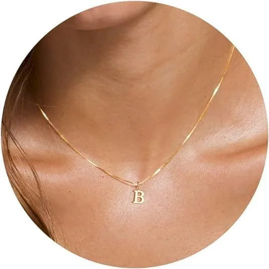 A close-up of a gold plated alphabet initial necklace with the letter B worn around the neck.