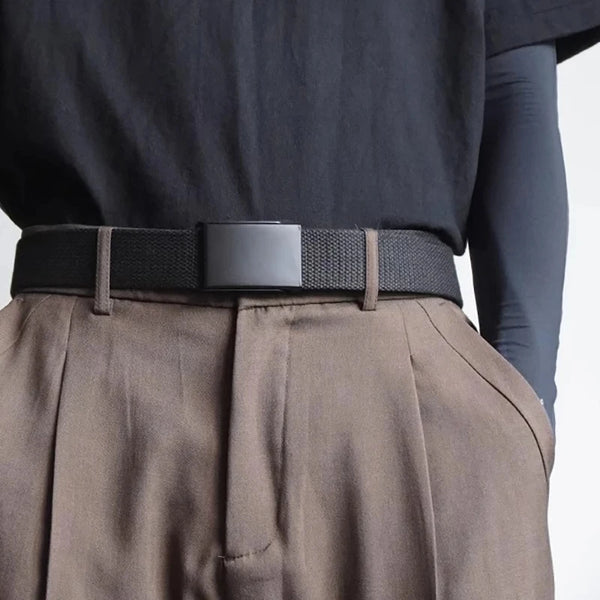 A close-up of a dark tactical canvas waist belt worn over a tan skirt and black top.