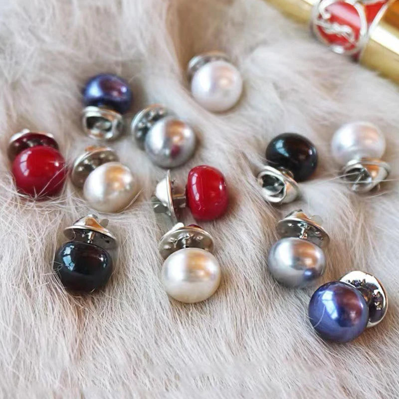 A collection of pearl and gemstone buttons in various colors and finishes scattered on soft white fur.