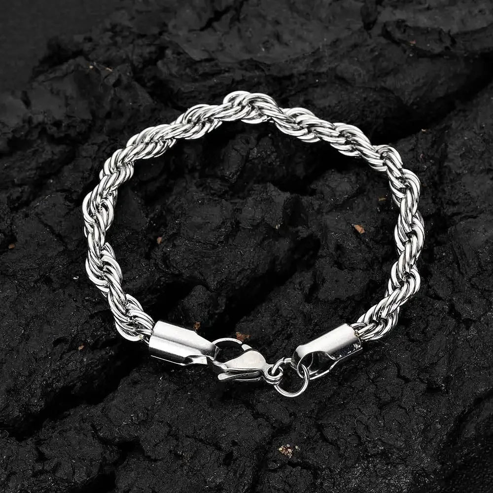 A silver stainless steel twisted chain bracelet lying on a dark, textured surface.