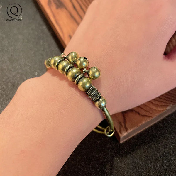 Gros plan d'un bracelet charm en cloche de laiton vintage porté à l'onde.