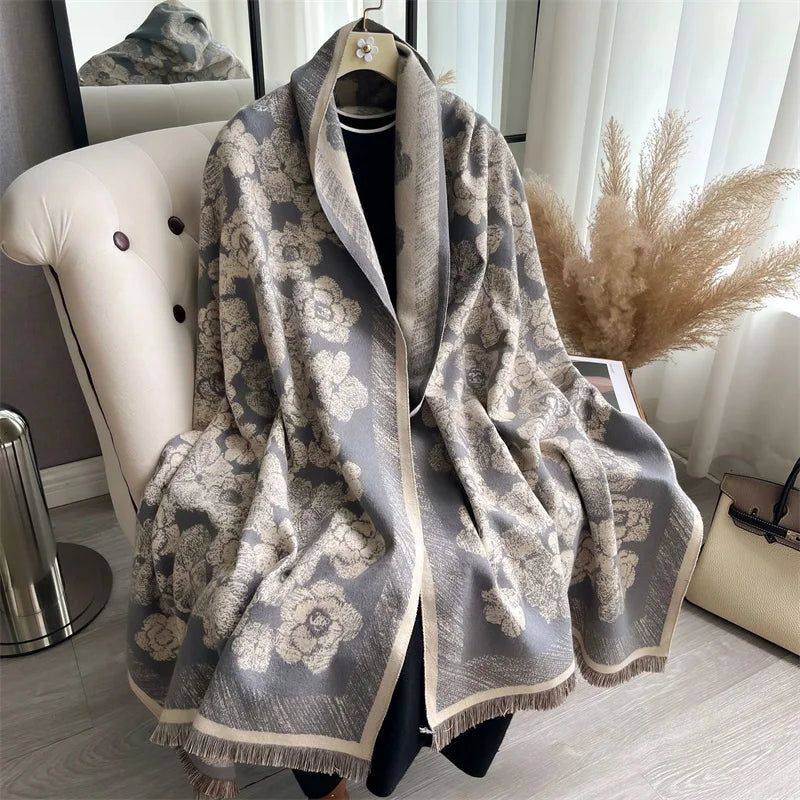A gray and beige plaid cashmere scarf draped over a hanger against a white background.
