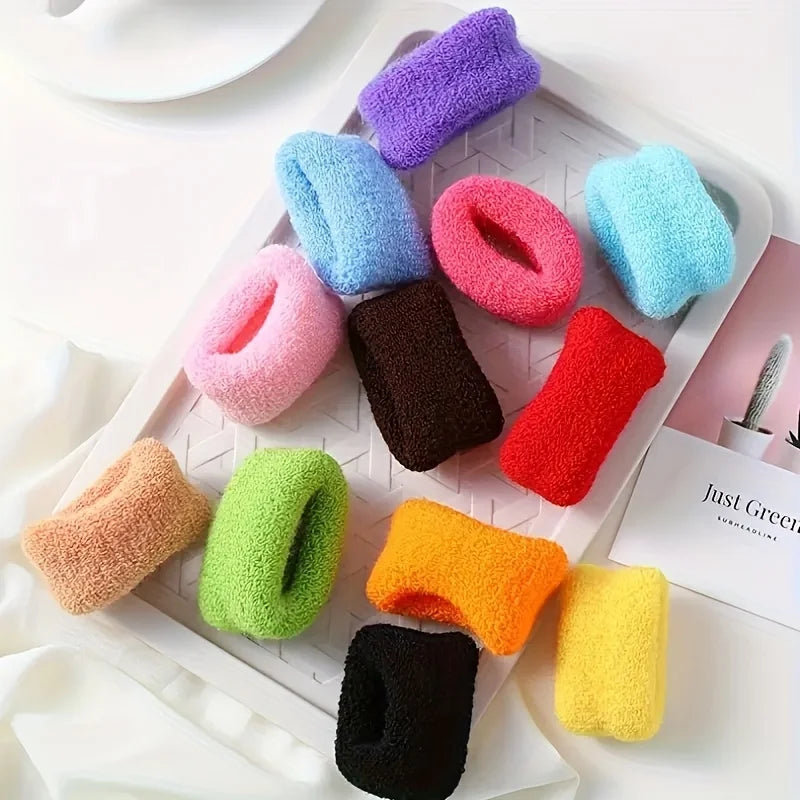 A variety of multi-colored cotton elastic hair ties in shades of purple, blue, pink, orange, green, and yellow are displayed 