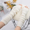 A pair of cream-colored knitted fingerless gloves displayed on a black wire stand.