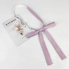 A lavender ribbon tie set with a delicate floral accent and a small charm, presented on a white card.