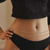 A close-up shot of a woman's midriff showing gold layered metal belly chains.