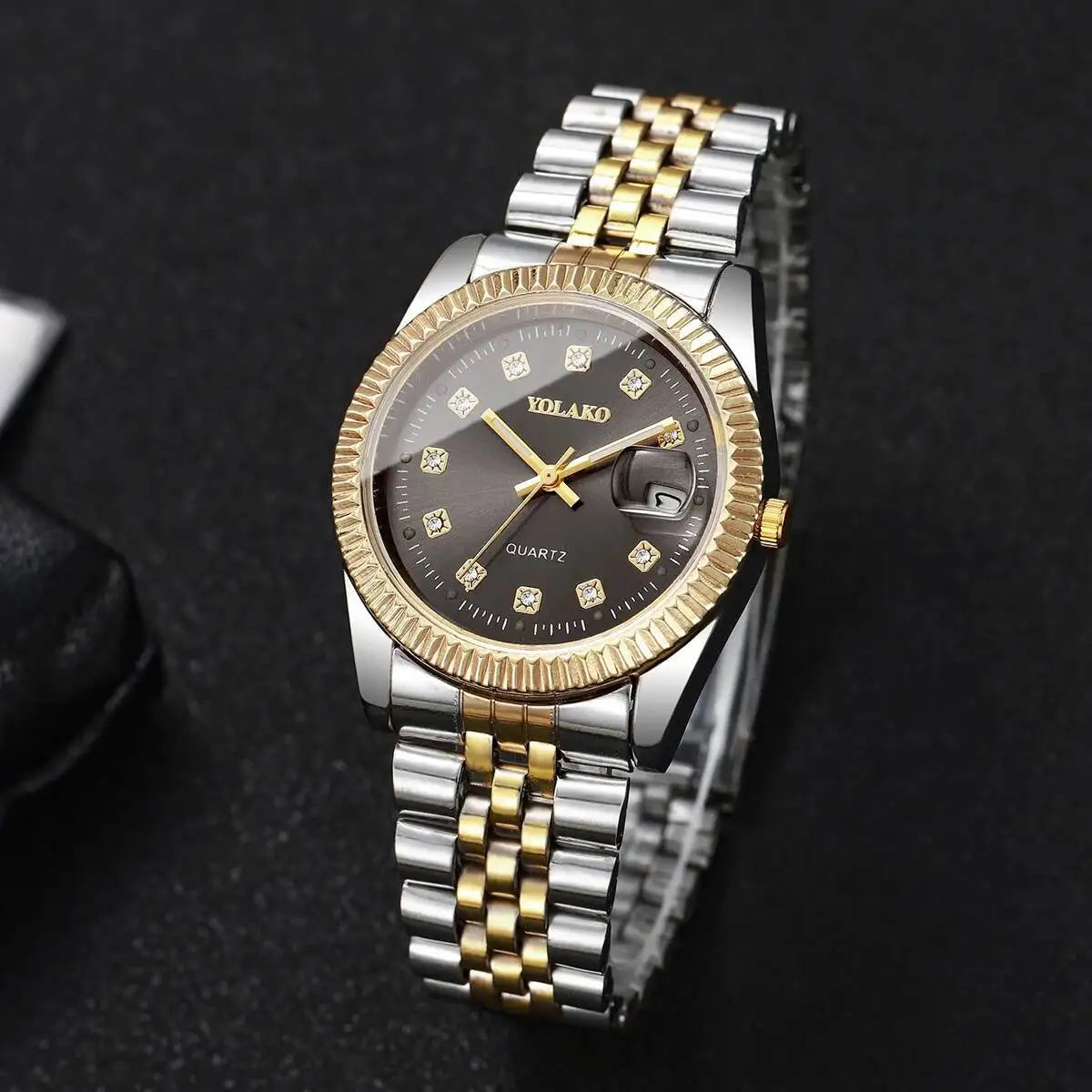 A silver-toned wristwatch with a gold-tone bracelet and a round face featuring a black dial and small diamond accents.