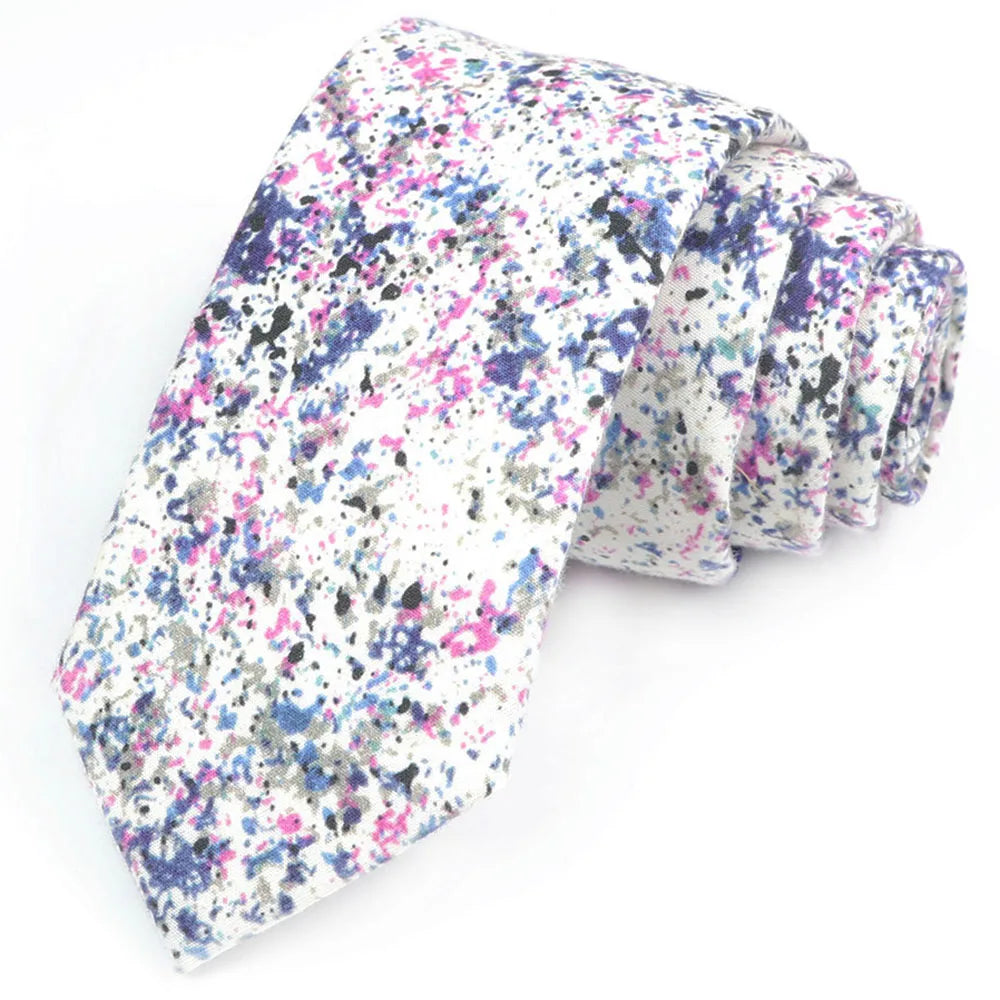 Nœud papillon en coton à motifs floraux plié, avec des pois roses, violets et gris sur fond blanc.