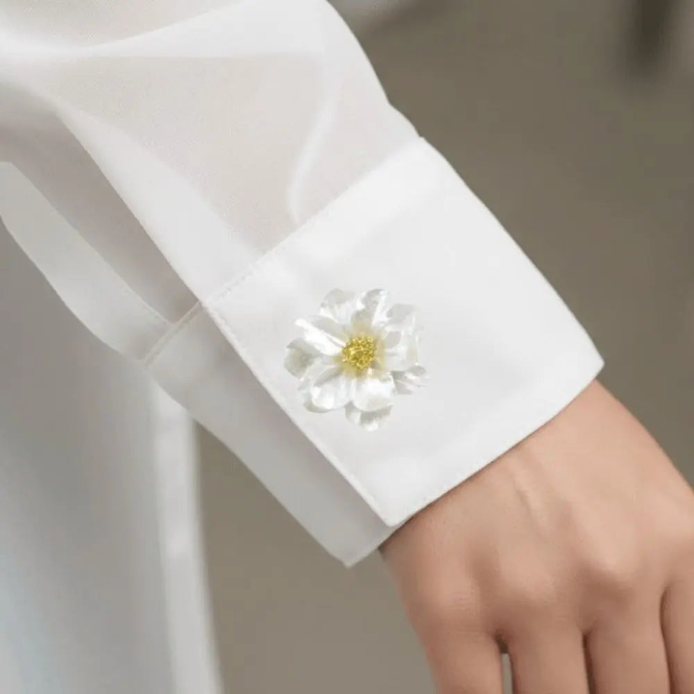 Close-up of a white dress shirt cuff featuring a delicate pearlescent flower button cover.