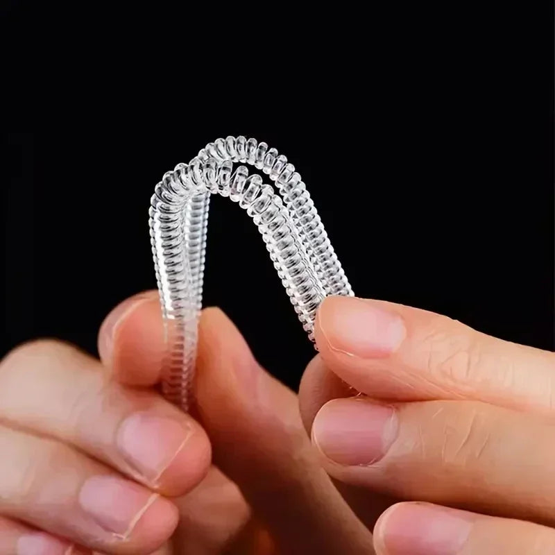 A pair of clear, flexible invisible ring sizer tools being held by a person.