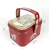 A red decorative tinplate candy box with a carrying loop and floral pattern.