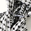 A close-up of a white and black patterned satin silk hijab fabric draped around a person's head.