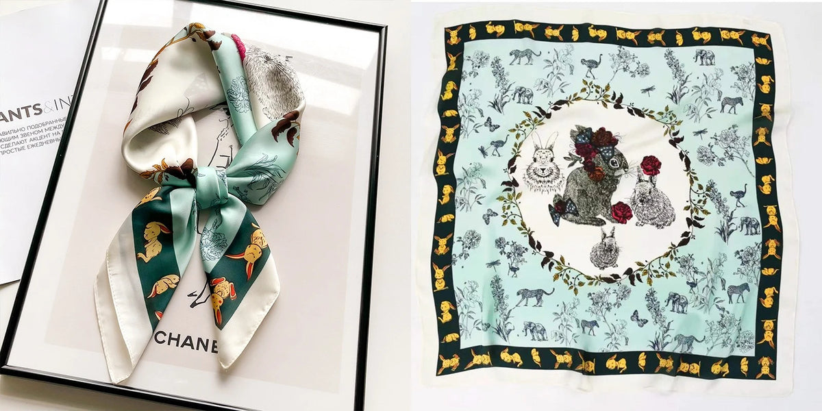 A silk scarf featuring a floral print with gold accents and various animal motifs on a light mint green background.