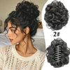A woman shows off a voluminous curly messy bun hairstyle with a black claw clip hair accessory.