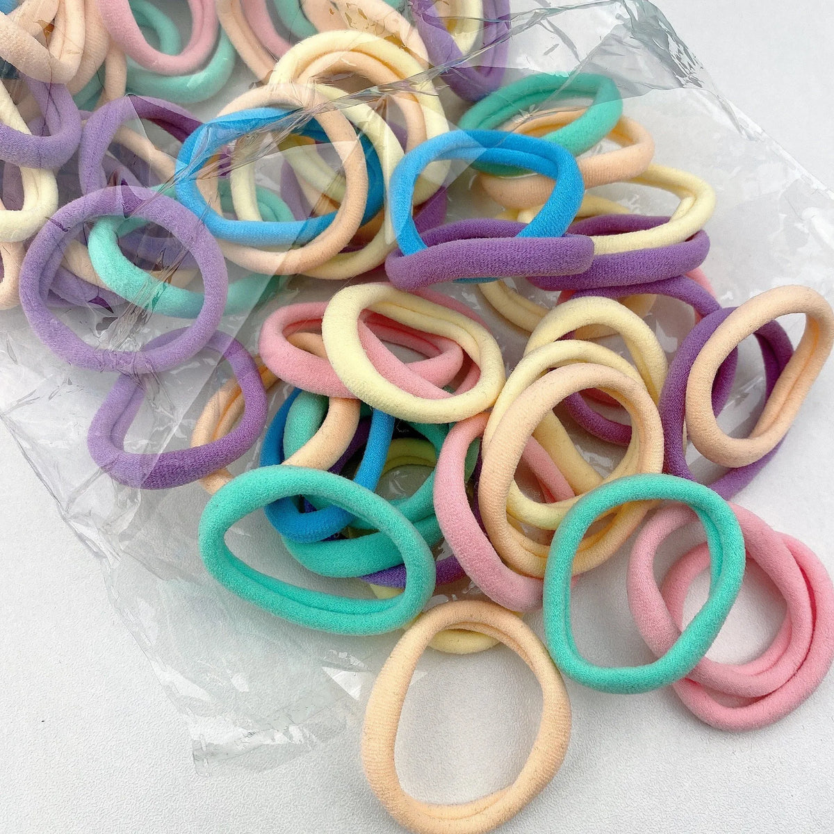 A collection of colorful elastic hair bands in various pastel shades like pink, blue, purple, and yellow.