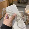 A hand holds clear anti-blue light frames for glasses on a white surface.