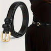 Black leather double loop fashion belt with a gold buckle shown next to a black dress.