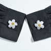 Pair of black fabric button covers with white pearl flower accents.