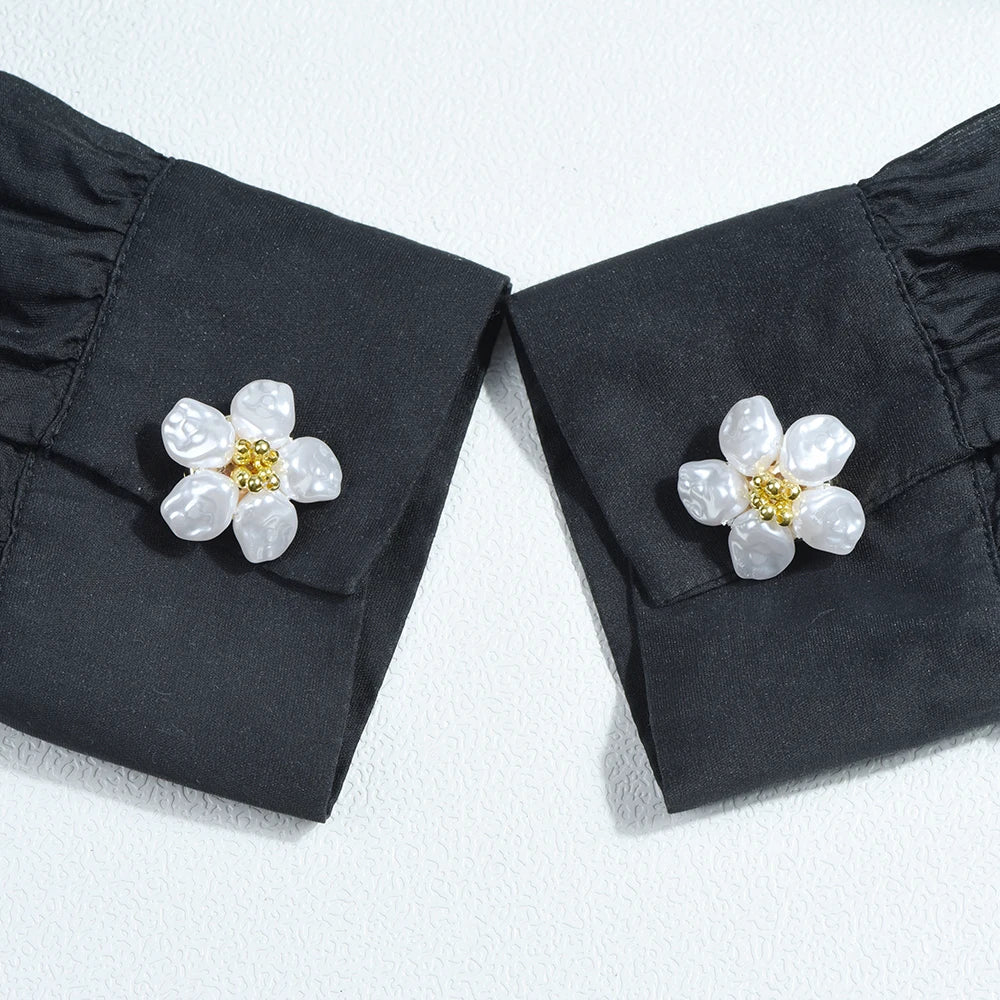 Pair of black fabric button covers with white pearl flower accents.
