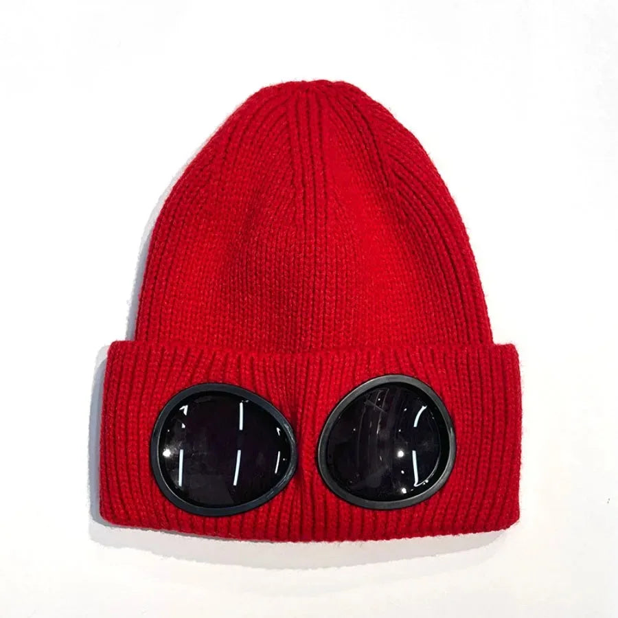 A bright red knit hat with black round goggles on the front