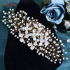 A delicate bridal headband or tiara made of clear rhinestones and small white flowers on a dark velvet background.