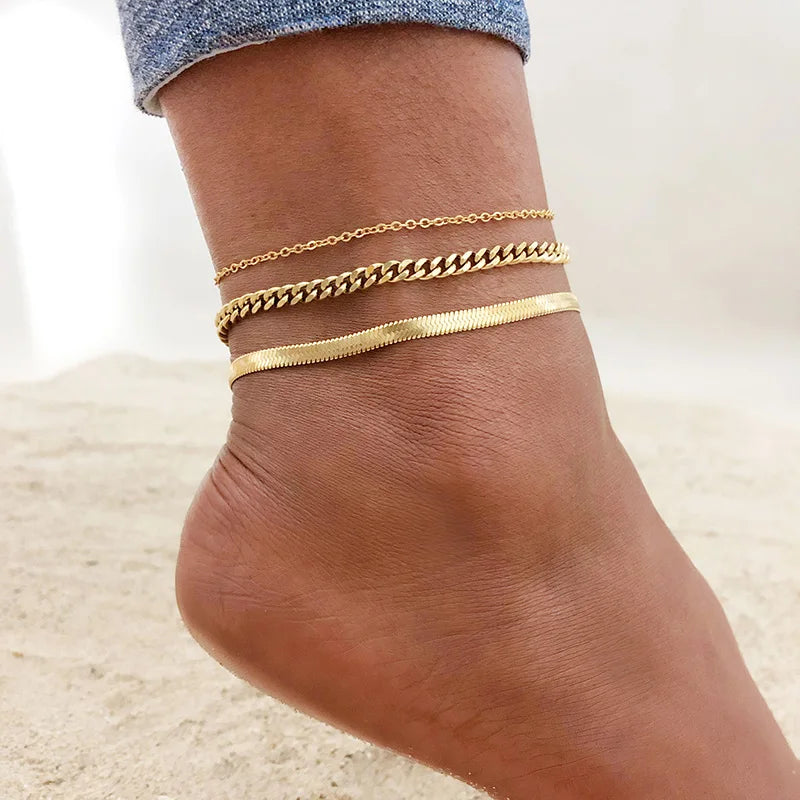 Gold stainless steel snake chain anklet worn on a woman's ankle.