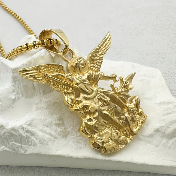 Gold-toned stainless steel cross pendant necklace featuring an angel figure on a white fabric background.