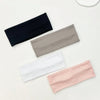 A set of four knitted hair bands in navy blue, gray, white, and pink laid diagonally on a light surface.