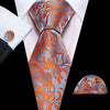 A close-up of a men's silk jacquard tie featuring an orange and gray floral pattern worn with a white dress shirt.