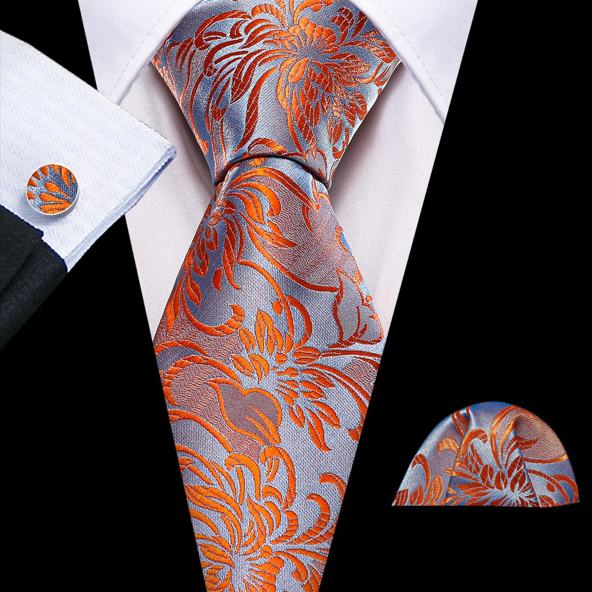 A close-up of a men's silk jacquard tie featuring an orange and gray floral pattern worn with a white dress shirt.